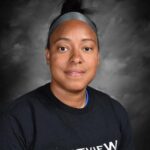 A woman with short hair wearing a black shirt with "Westview" printed on it, against a gray background.