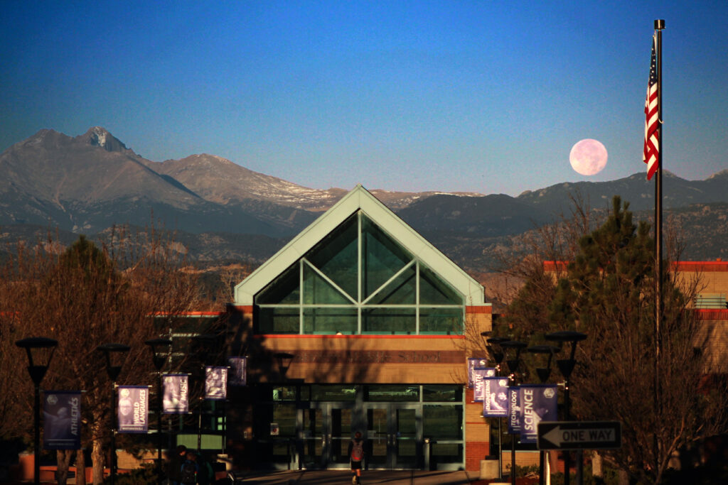 Beautiful picture of Westview Middle School with Longs Peak and a full moon in the background.