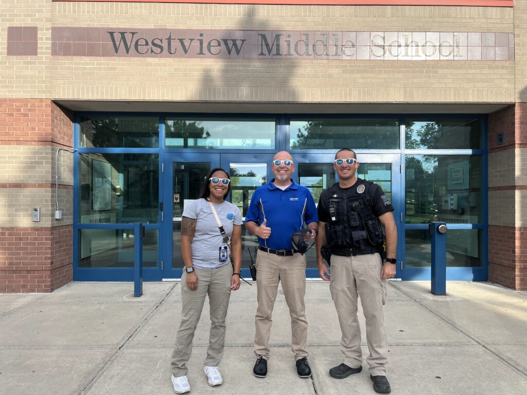 Two westview employees, a female teacher and male assistant principal, standing next to a campus security officer in front of Westview MIddle School.