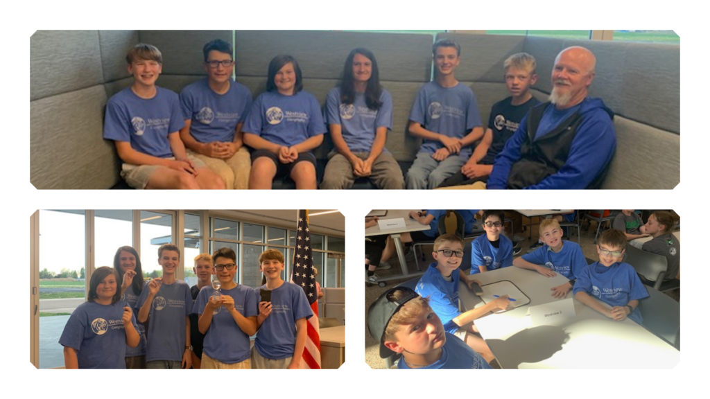 Group of students in blue shirts engaged in activities, some posing for a photo, others working at tables.