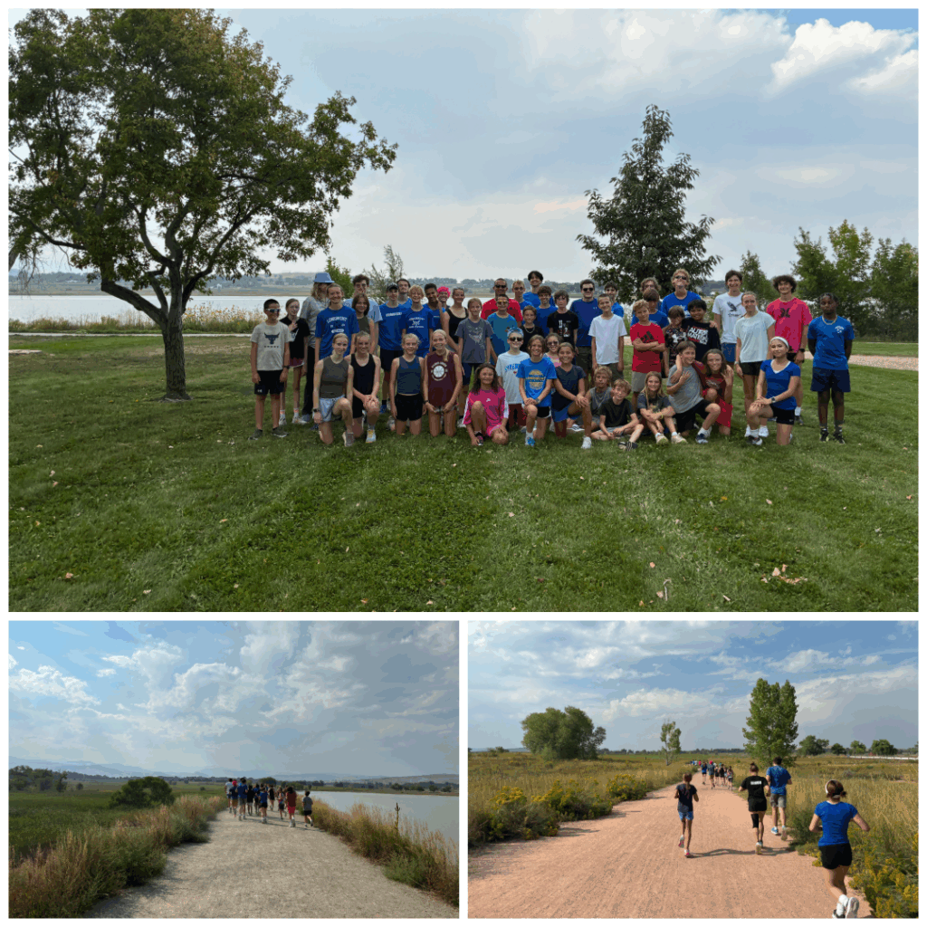 Group photo of a youth sports team outdoors, with scenic views of grass, trees, and a lake in the background.