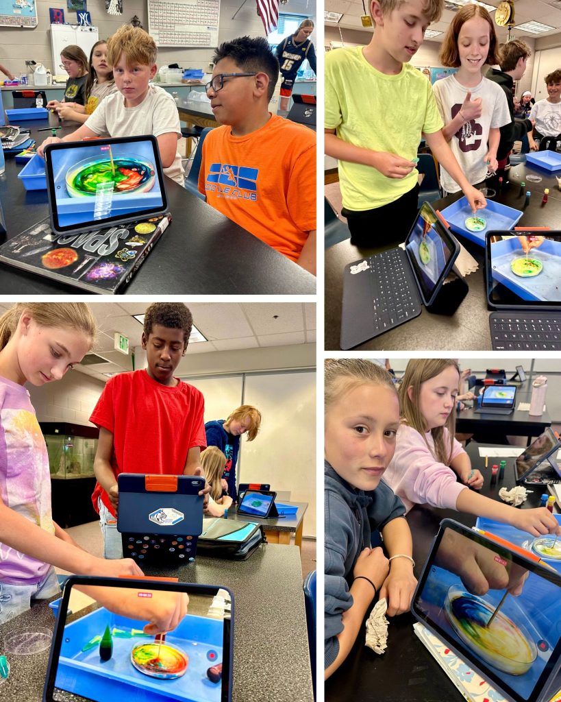 Students engaged in a science experiment, using tablets to observe colorful liquid mixtures in a classroom setting.